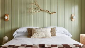 Una cama bien hecha con un edredón estampado, una rama decorativa como adorno de pared y dos lámparas de pared.