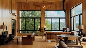 A spacious room with large windows, wooden furniture, and a fireplace. - Laurel Lake Placid (Lake Placid)
