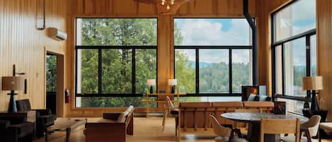 Una habitación amplia con ventanas grandes, muebles de madera y una chimenea.