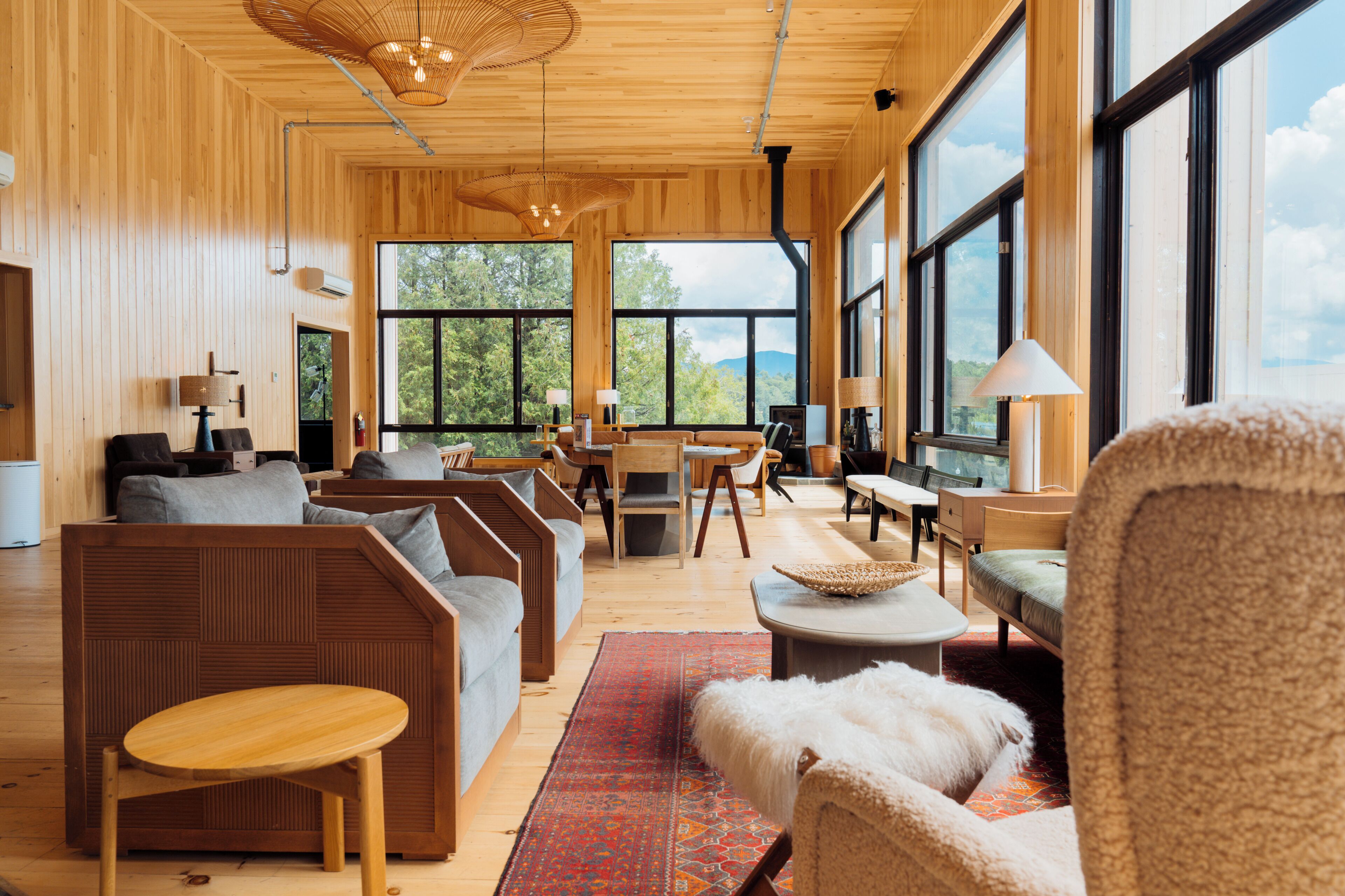 A spacious living area with wooden walls, large windows, and a variety of seating arrangements.