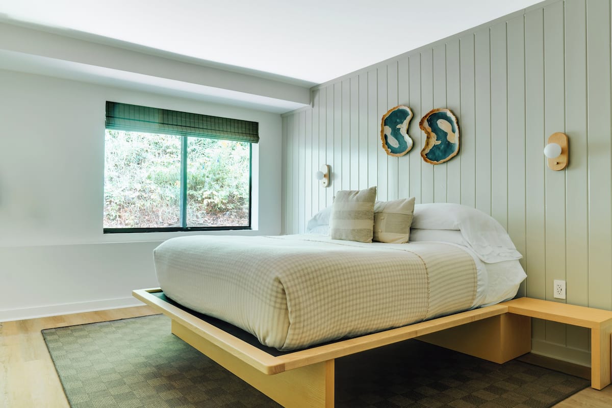 A bedroom with a bed, a window, a bedside table, and wall-mounted decor.