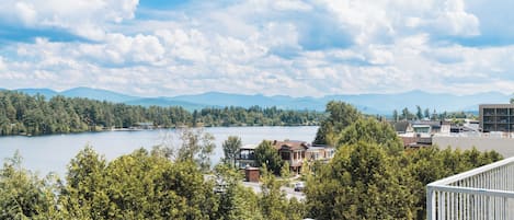A lakeside view with a house in the foreground and mountains in the background.