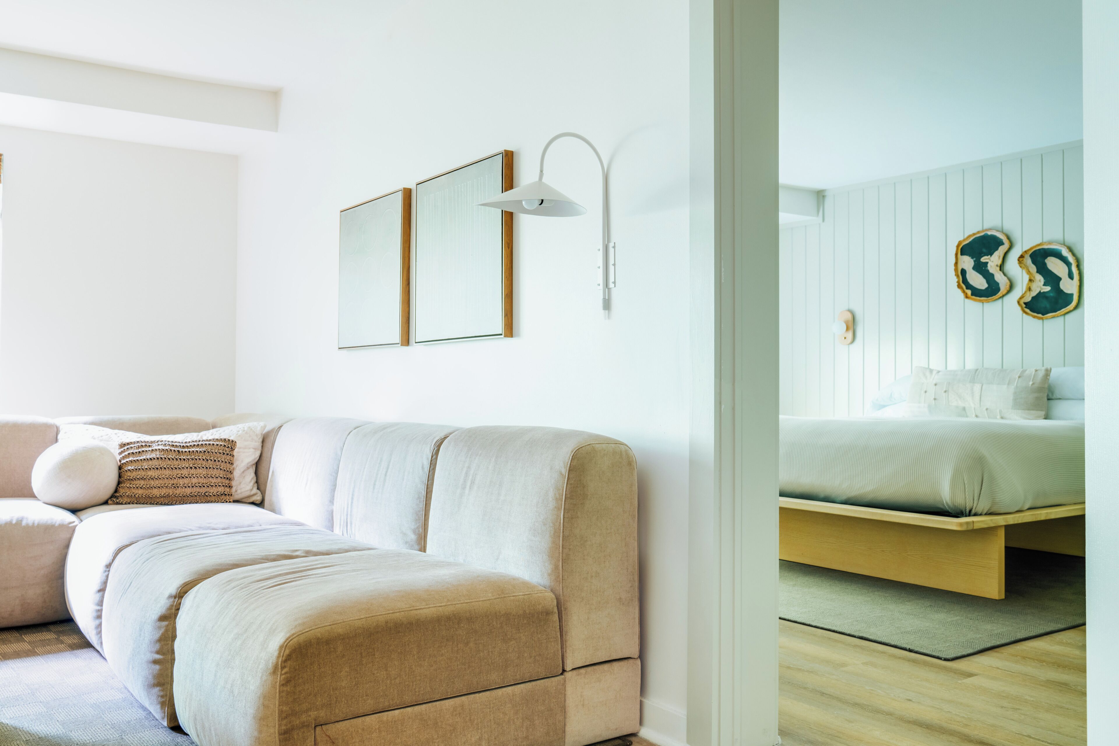 A modern bedroom with a bed, a sofa, and a wall-mounted light fixture.