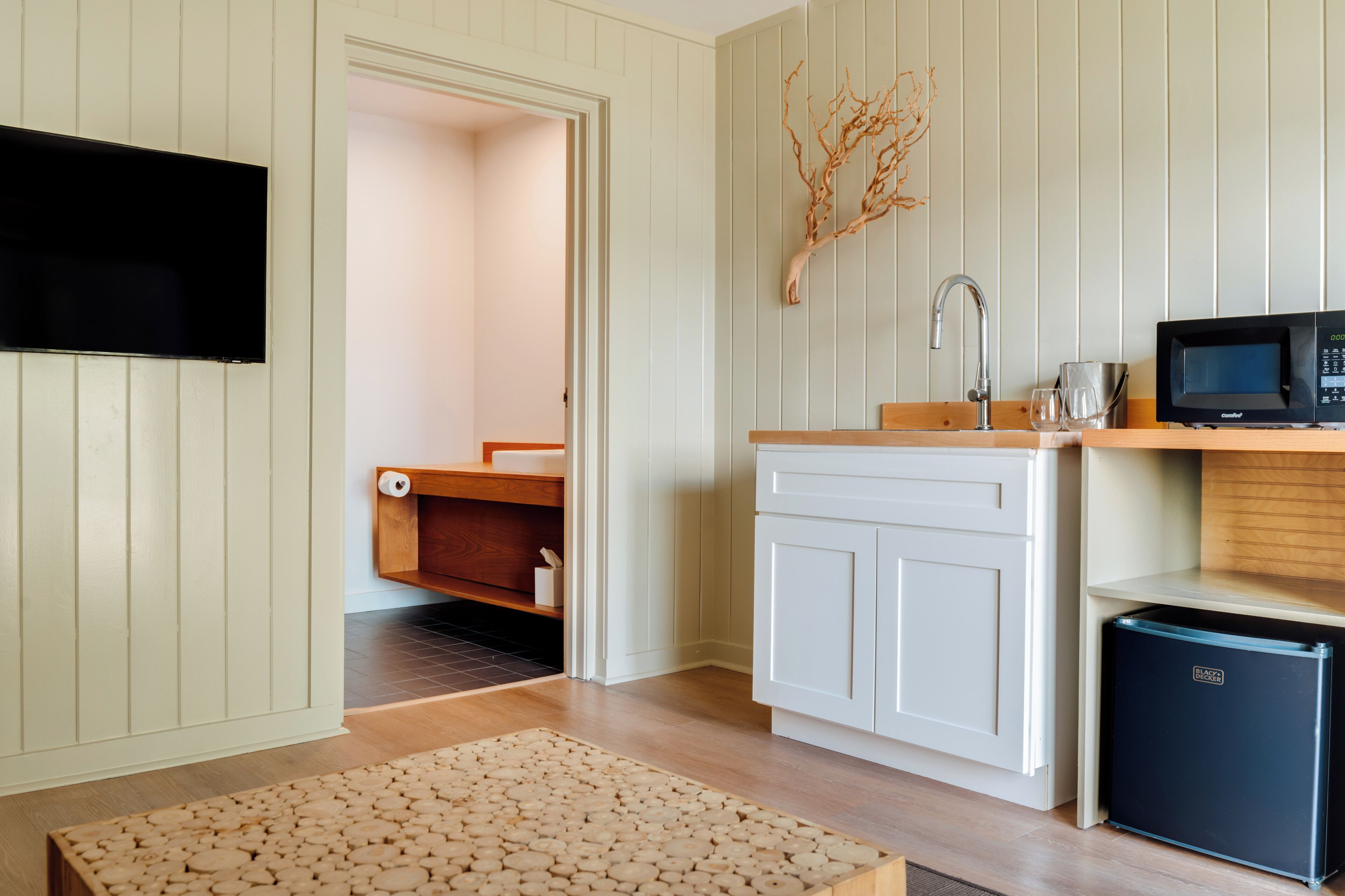 A compact kitchen with a microwave, sink, and a small refrigerator.