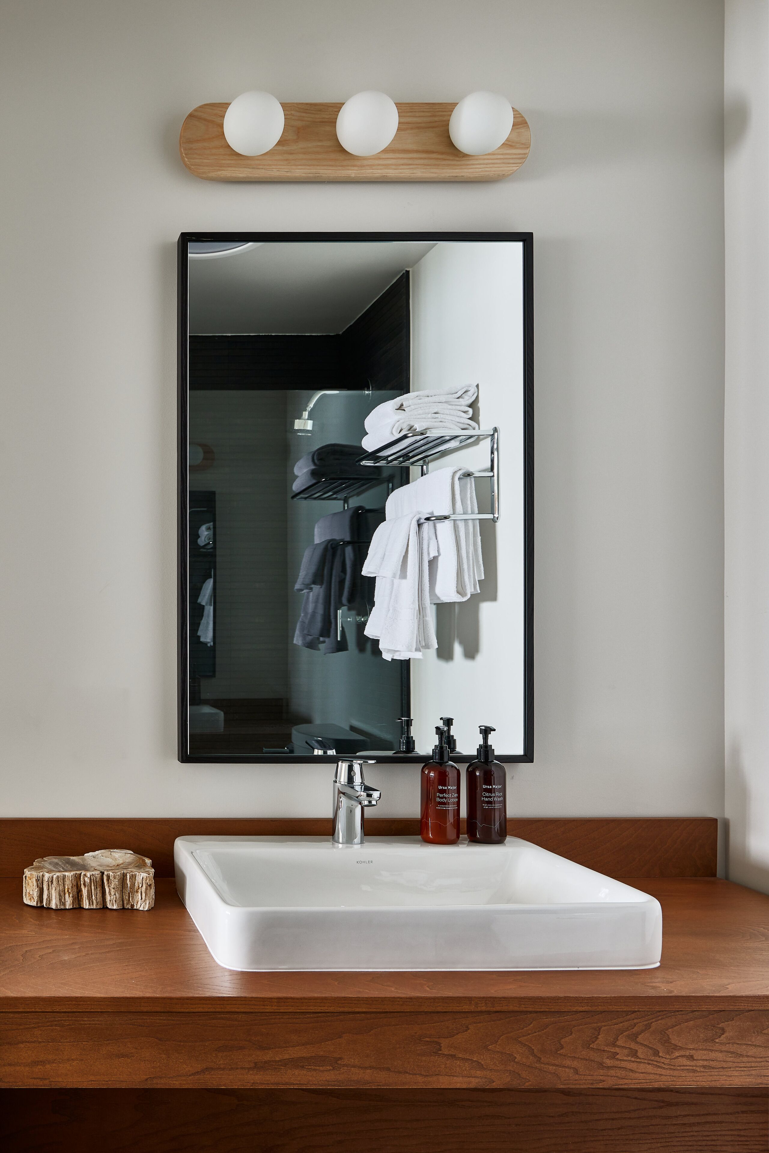 Un baño con un espejo grande, un lavabo blanco y un mueble de tocador de madera.