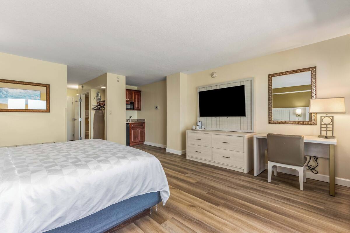 Ein Schlafzimmer mit einem Bett, einem Schreibtisch, einem Stuhl, einer Kommode und einem Fernseher.