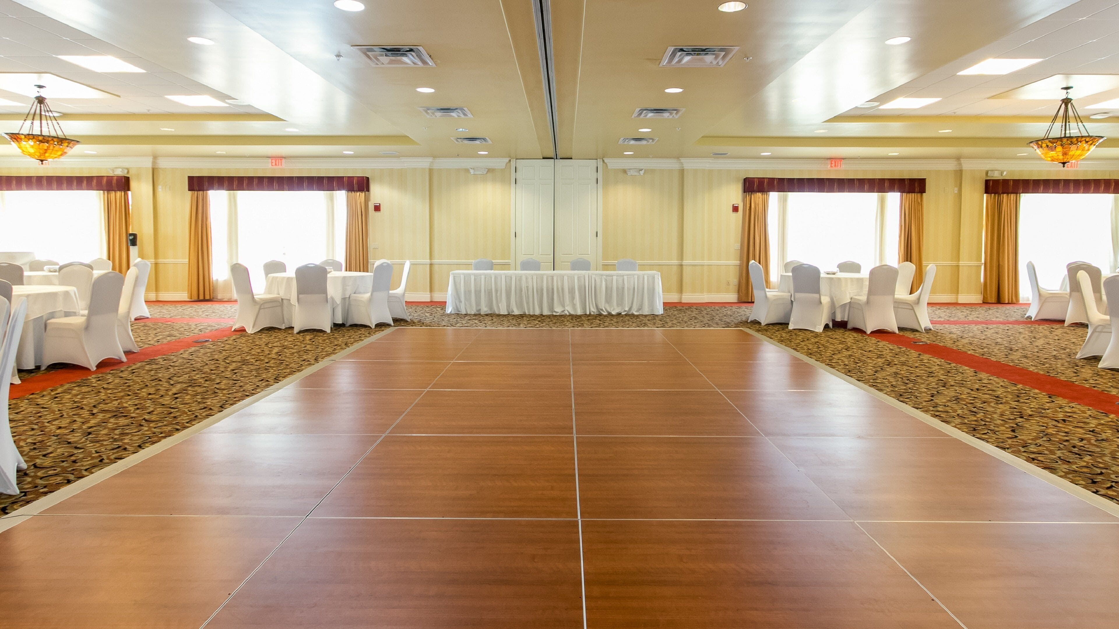 A conference room with a long table and chairs, carpeted floors, and large windows with curtains.