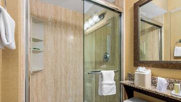 Un baño moderno con ducha de vidrio, lavamanos blanco y espejo con marco decorativo.