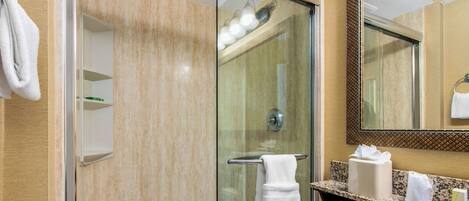 A modern bathroom with a glass-enclosed shower, a white sink, and a mirror with a decorative frame.