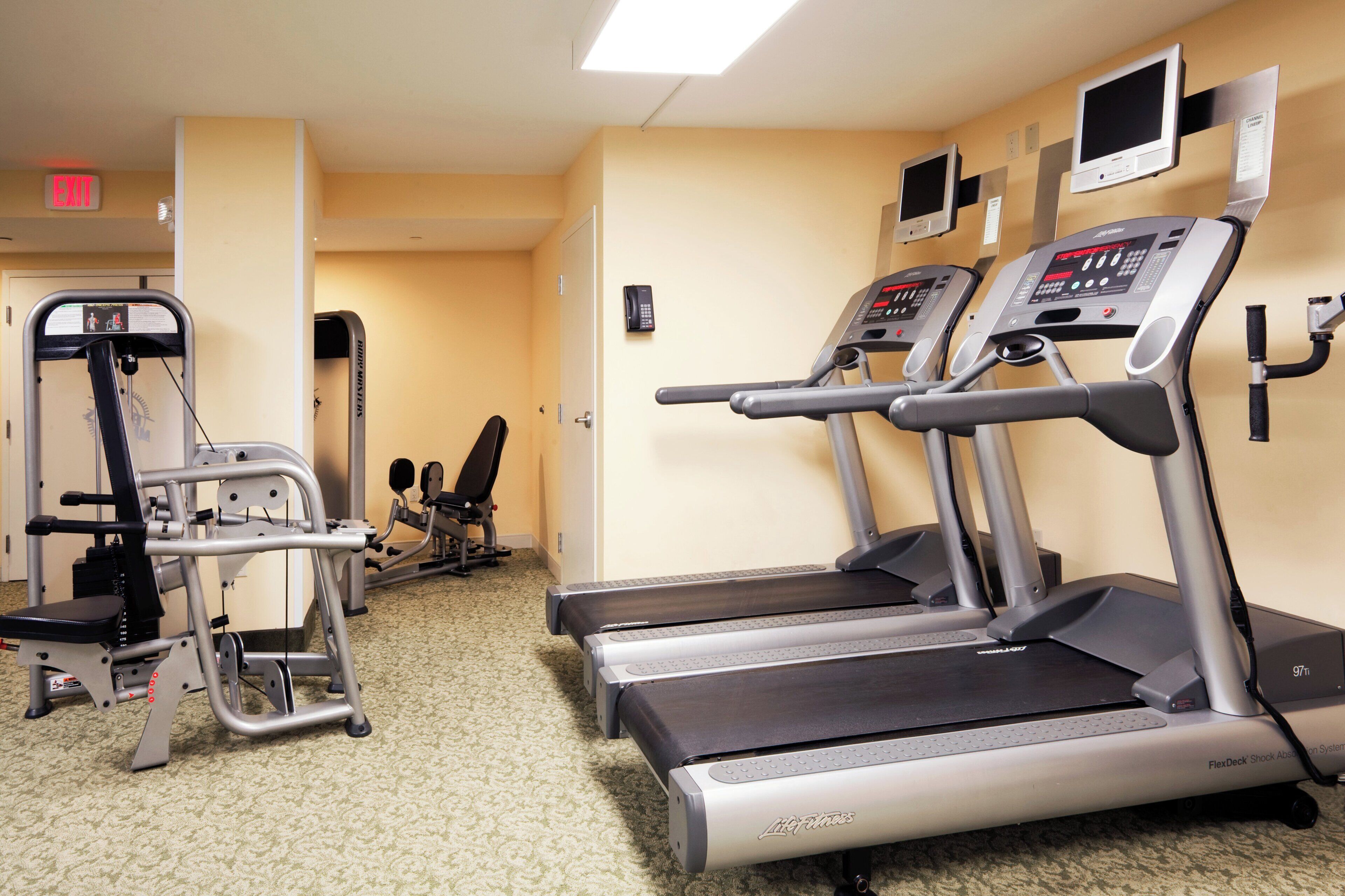 A fitness center with treadmills, a weight machine, and a wall-mounted TV.