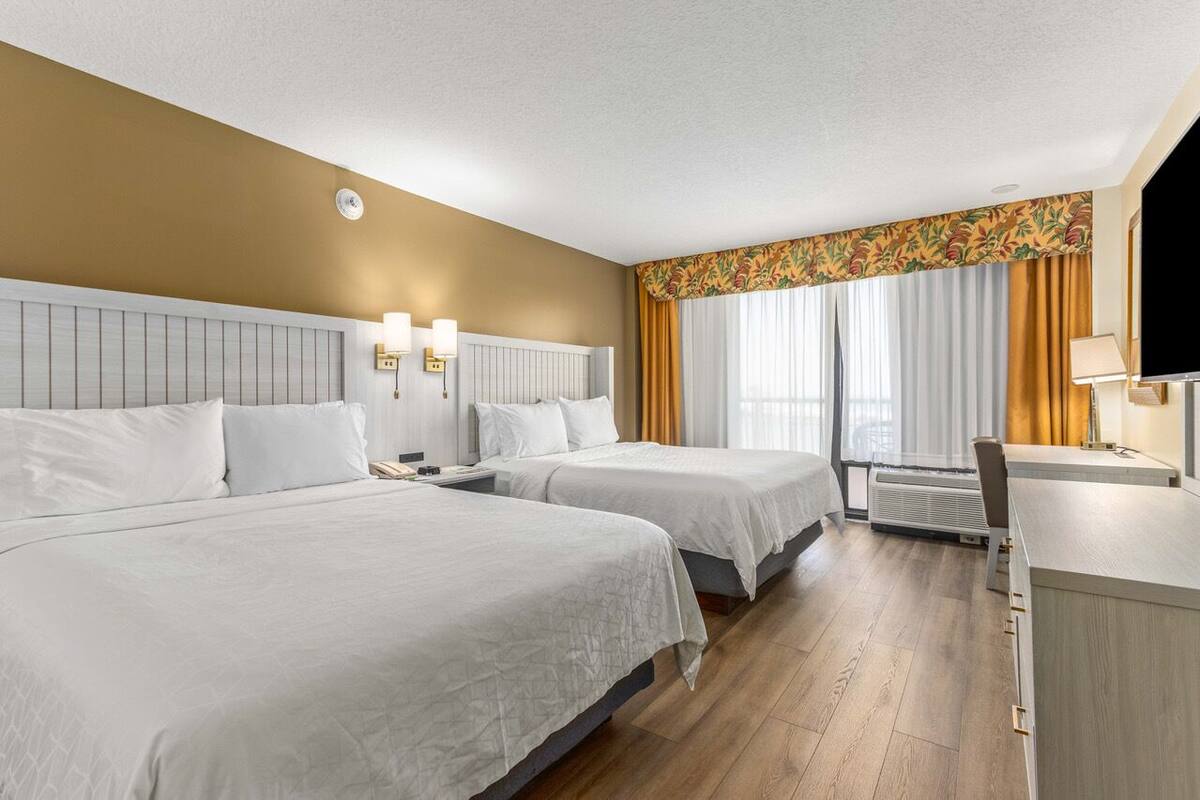 Ein Hotelzimmer mit zwei Betten, einem Schreibtisch und einem Fernseher.