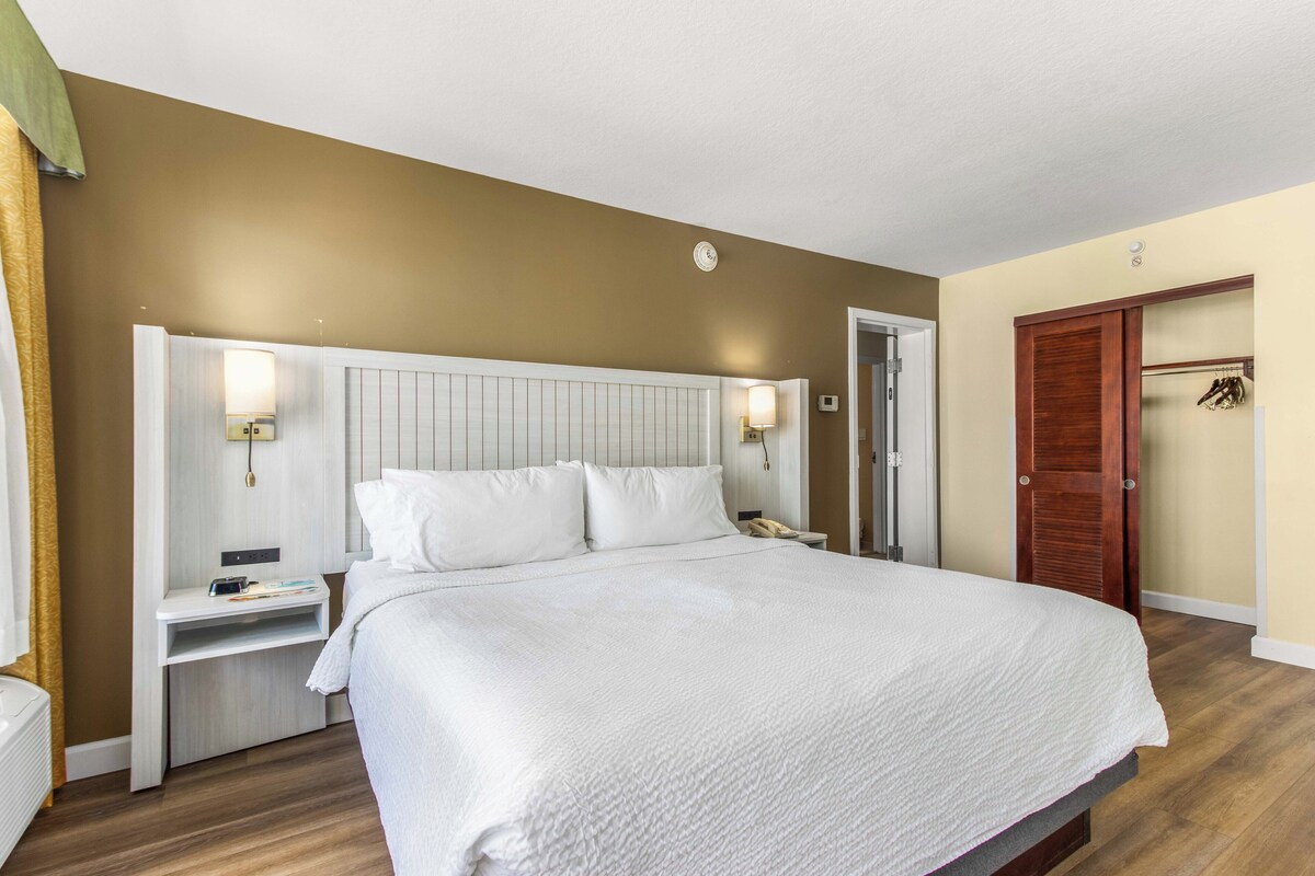 Ein Hotelzimmer mit einem großen Bett, Nachttischen, einem Kleiderschrank und einem Spiegel.