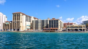 Un hôtel situé sur la côte, avec plusieurs étages, des balcons et un accès direct à la plage.