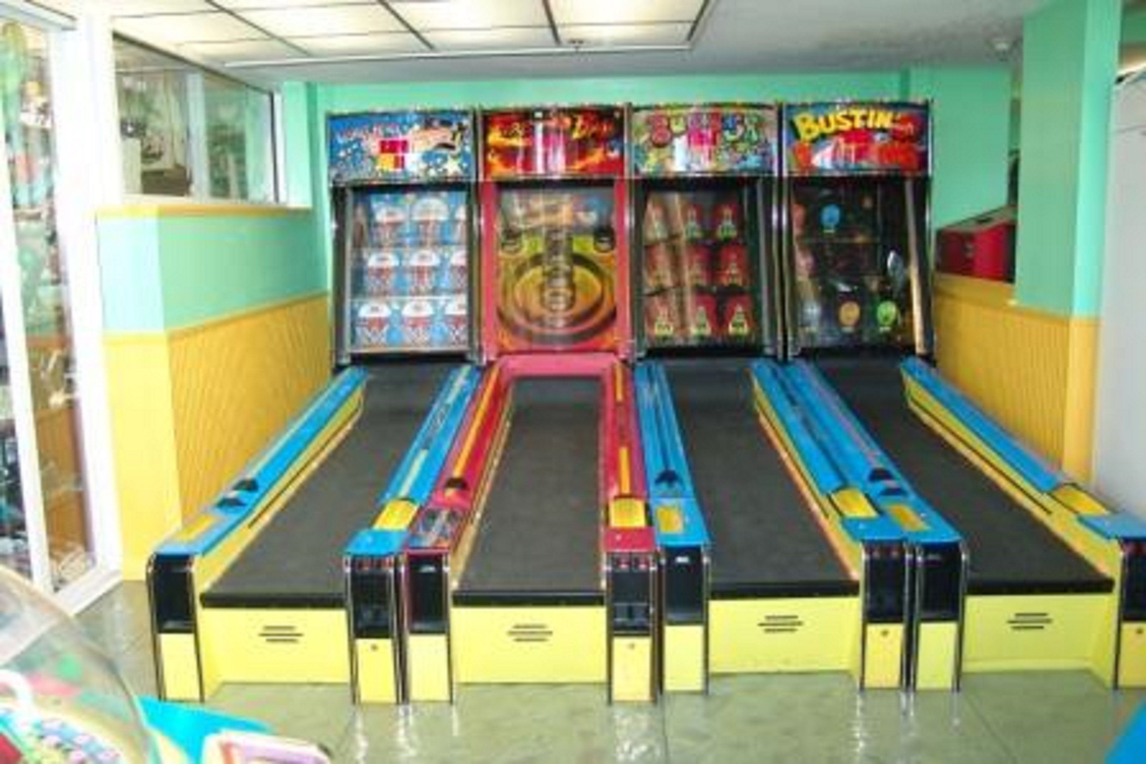 A row of arcade machines in a room with yellow walls and a green floor.