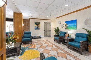 A lobby with wicker furniture, a patterned rug, and artwork on the walls.