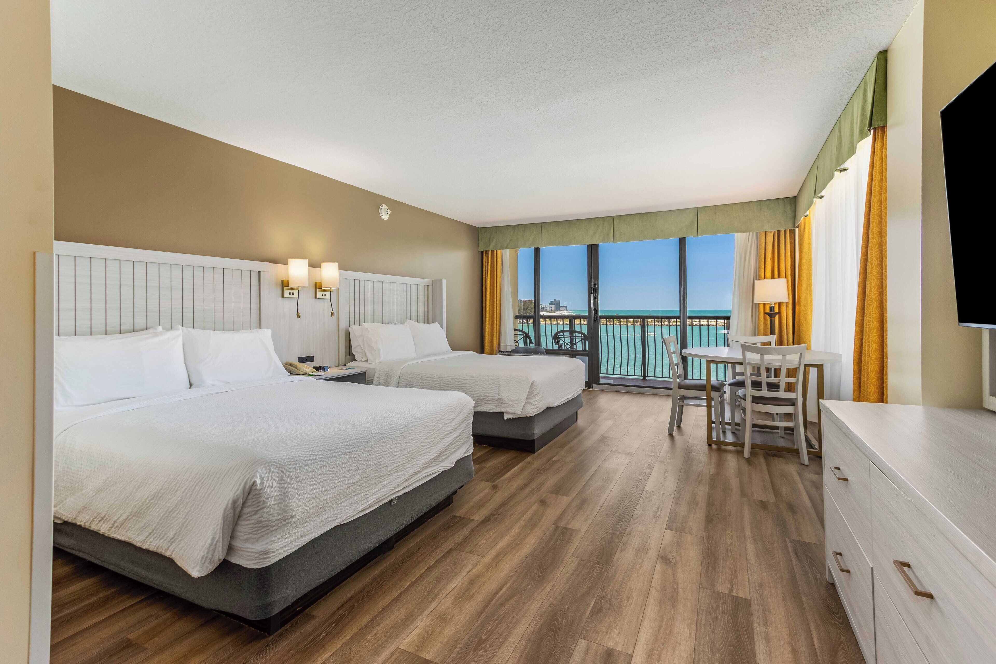 A hotel room with two beds, a dining table, and a TV.