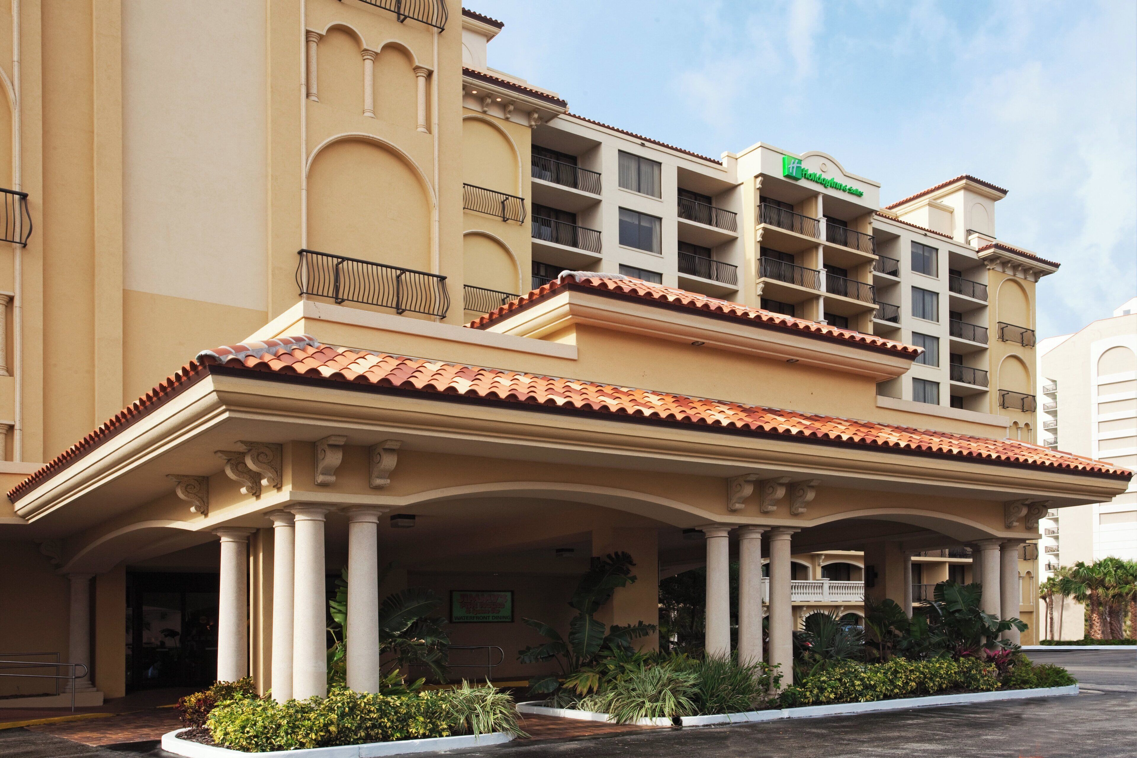 A hotel with a covered entrance, multiple balconies, and a sign indicating a dining area.