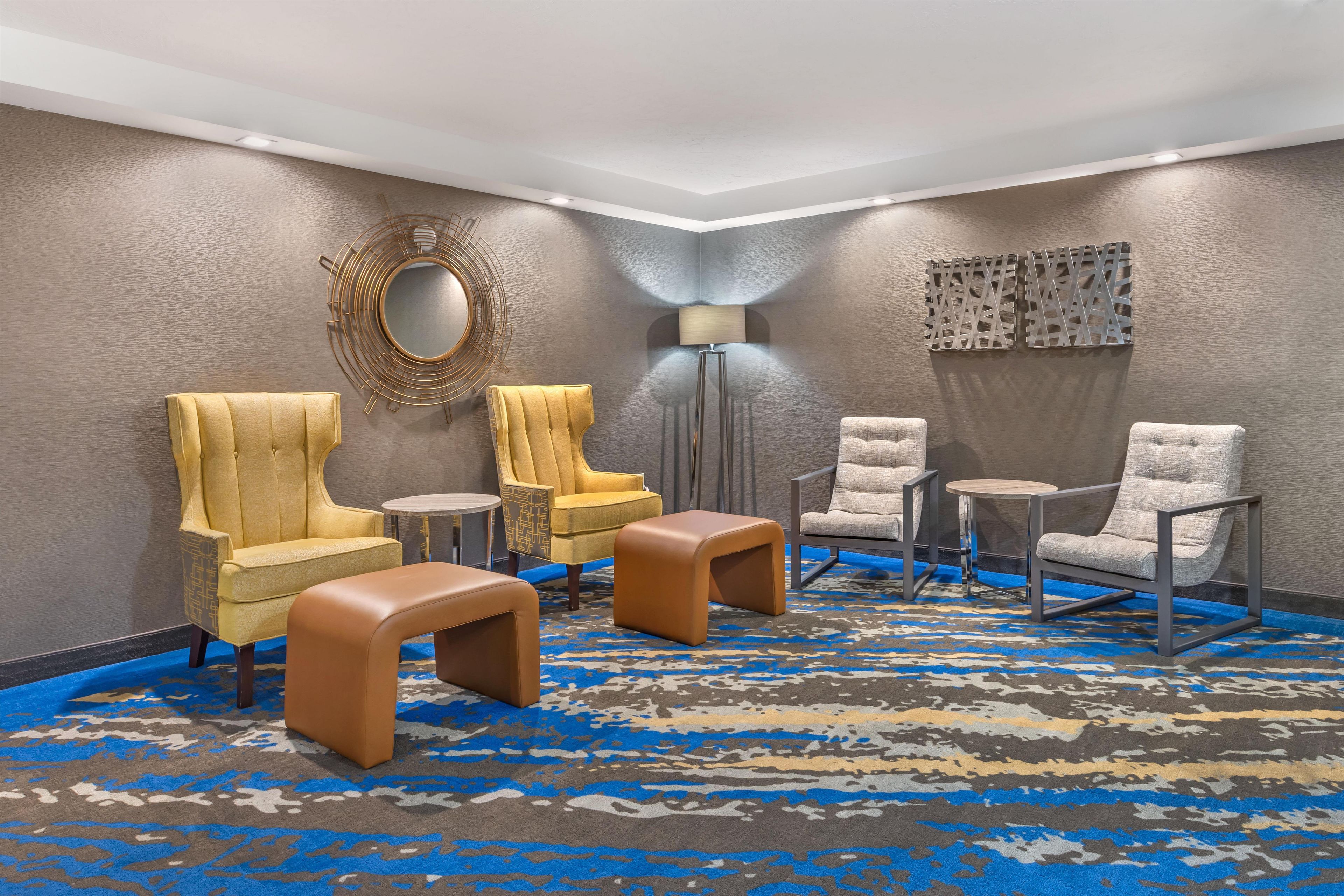 A room with four armchairs, a round table, and a floor lamp.