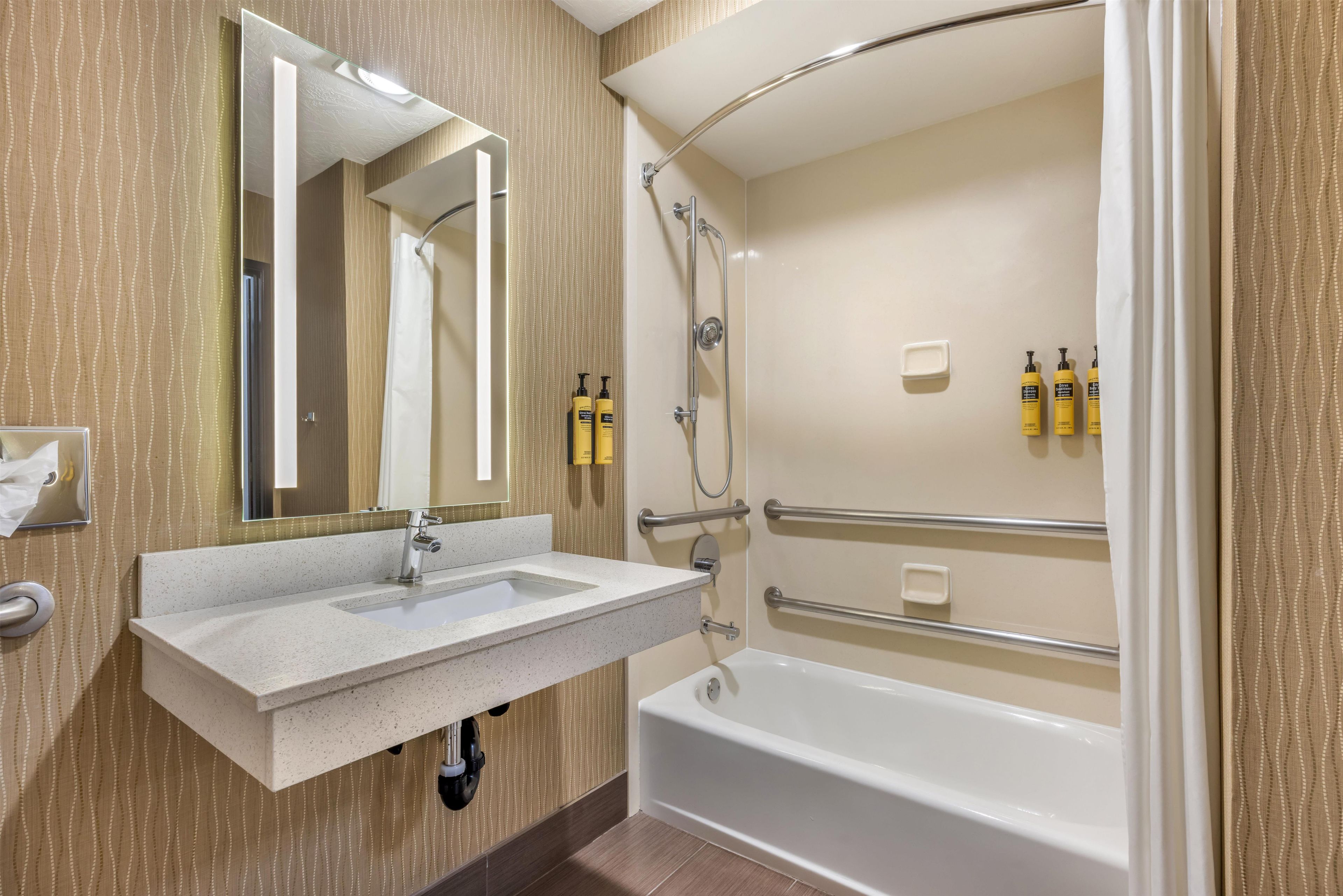 A modern bathroom with a sink, mirror, shower, and bathtub.