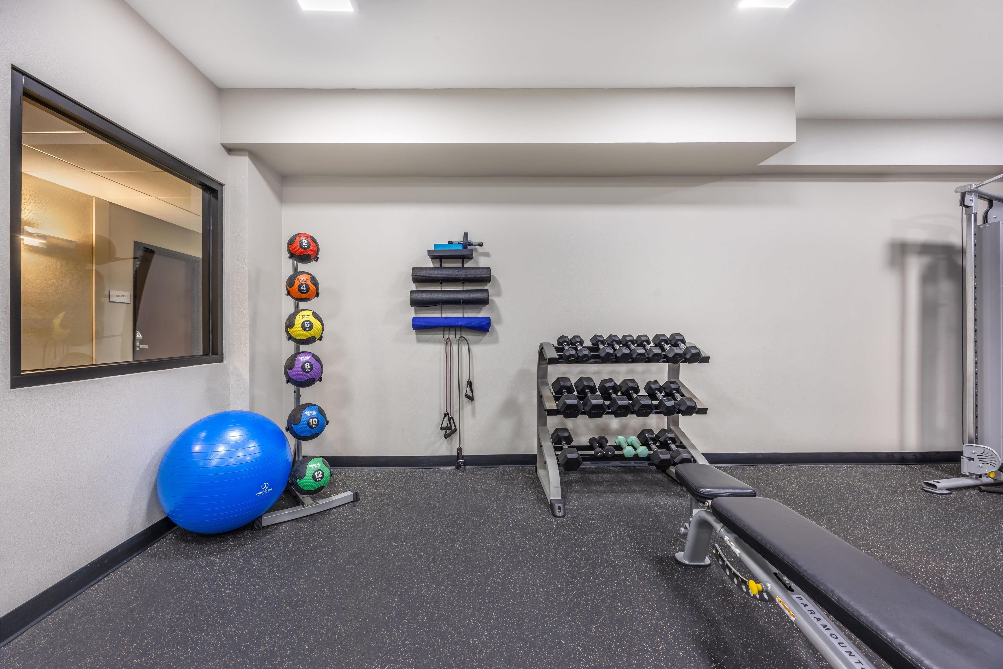 Un gimnasio con equipo de ejercicio, una pelota de ejercicio azul y un banco.