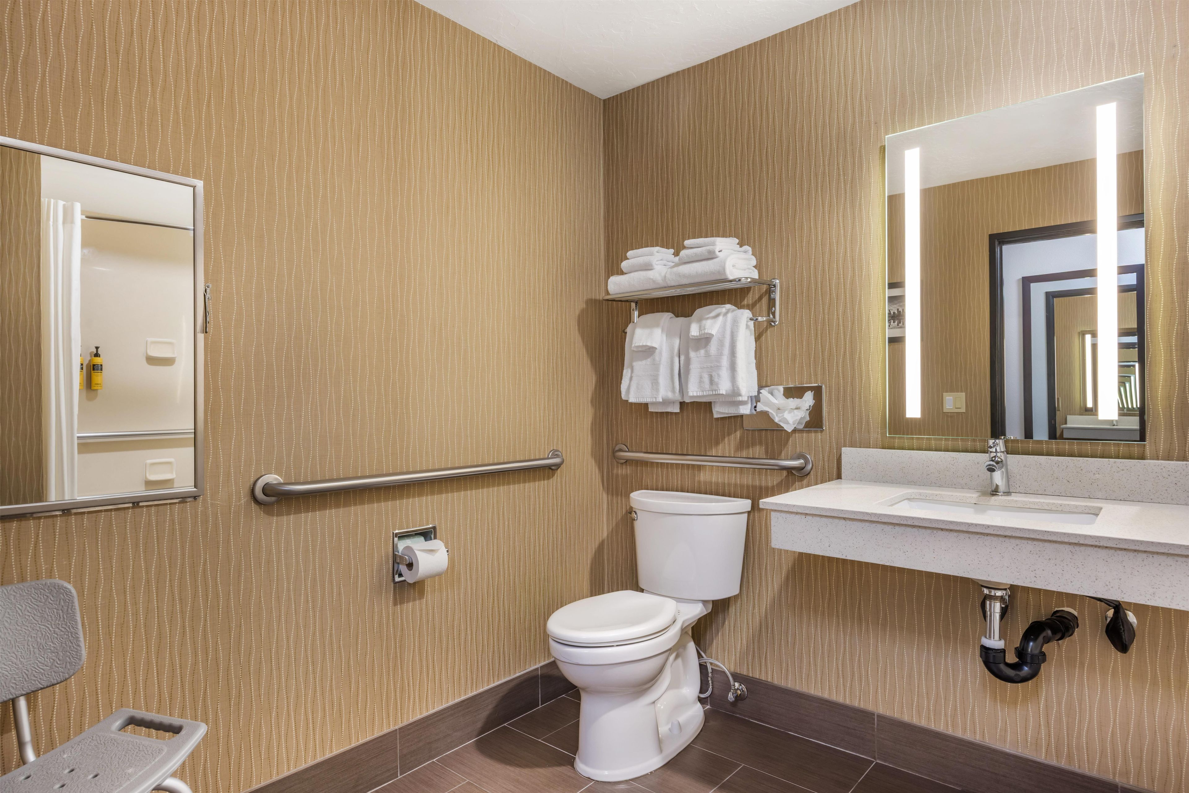 Ein Badezimmer mit Toilette, Waschbecken, Spiegel und Handtuchhalter.