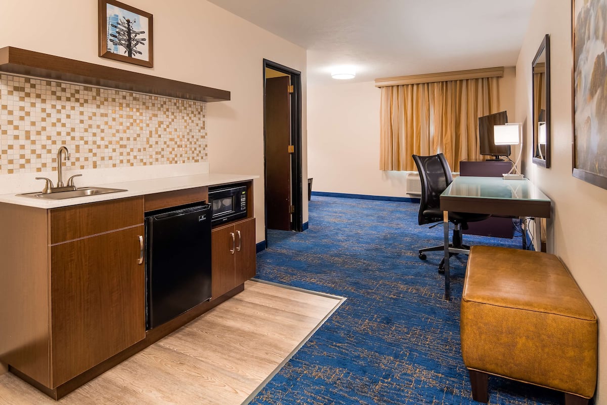 Une chambre d’hôtel compacte dotée d’une kitchenette, d’un petit coin repas et d’un banc.
