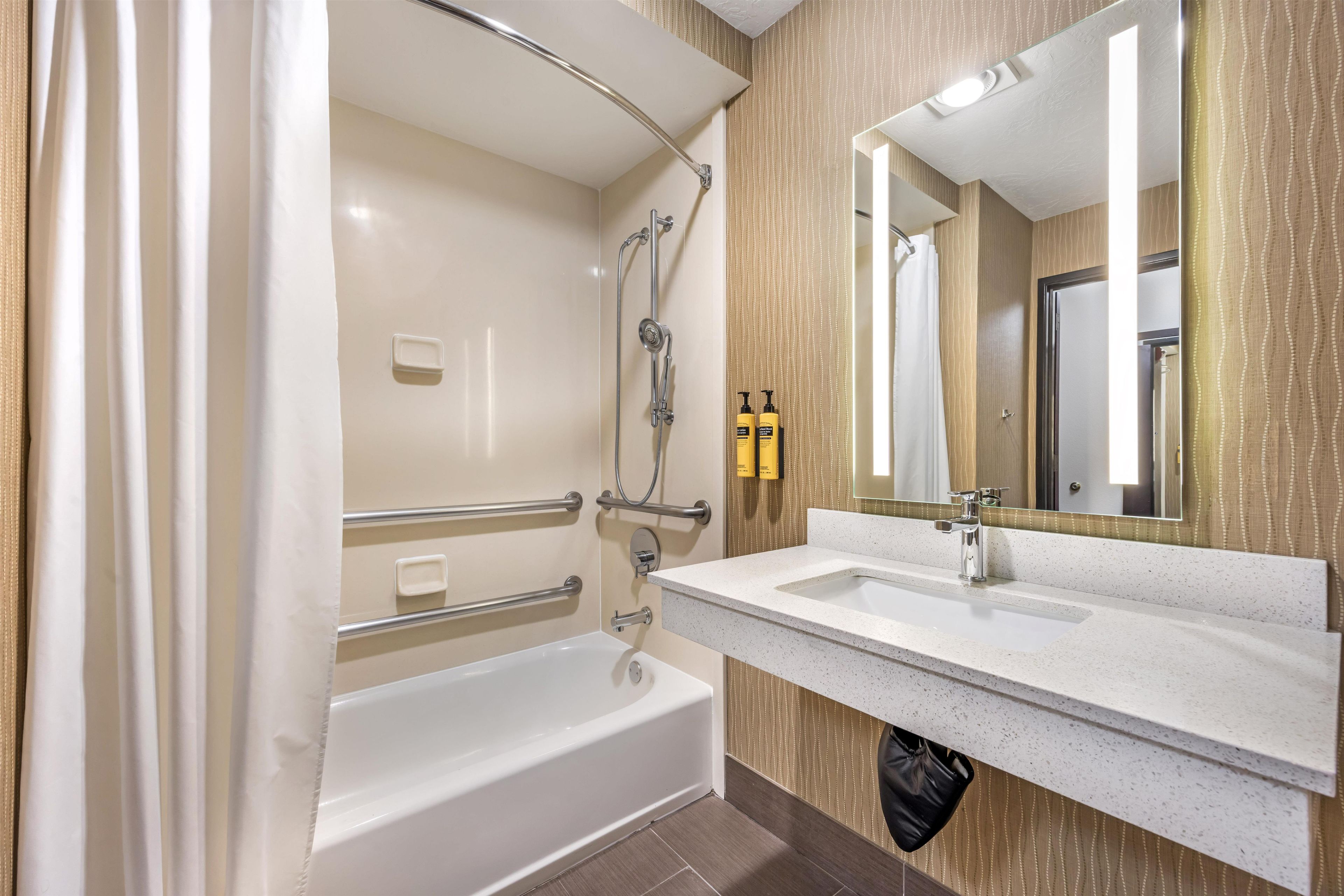 A modern bathroom with a bathtub, a sink, and a mirror.