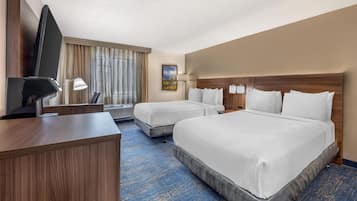 A hotel room with two beds, a desk, a TV, and a painting on the wall.