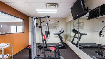 A fitness center with a treadmill, weight bench, and mirrored walls.