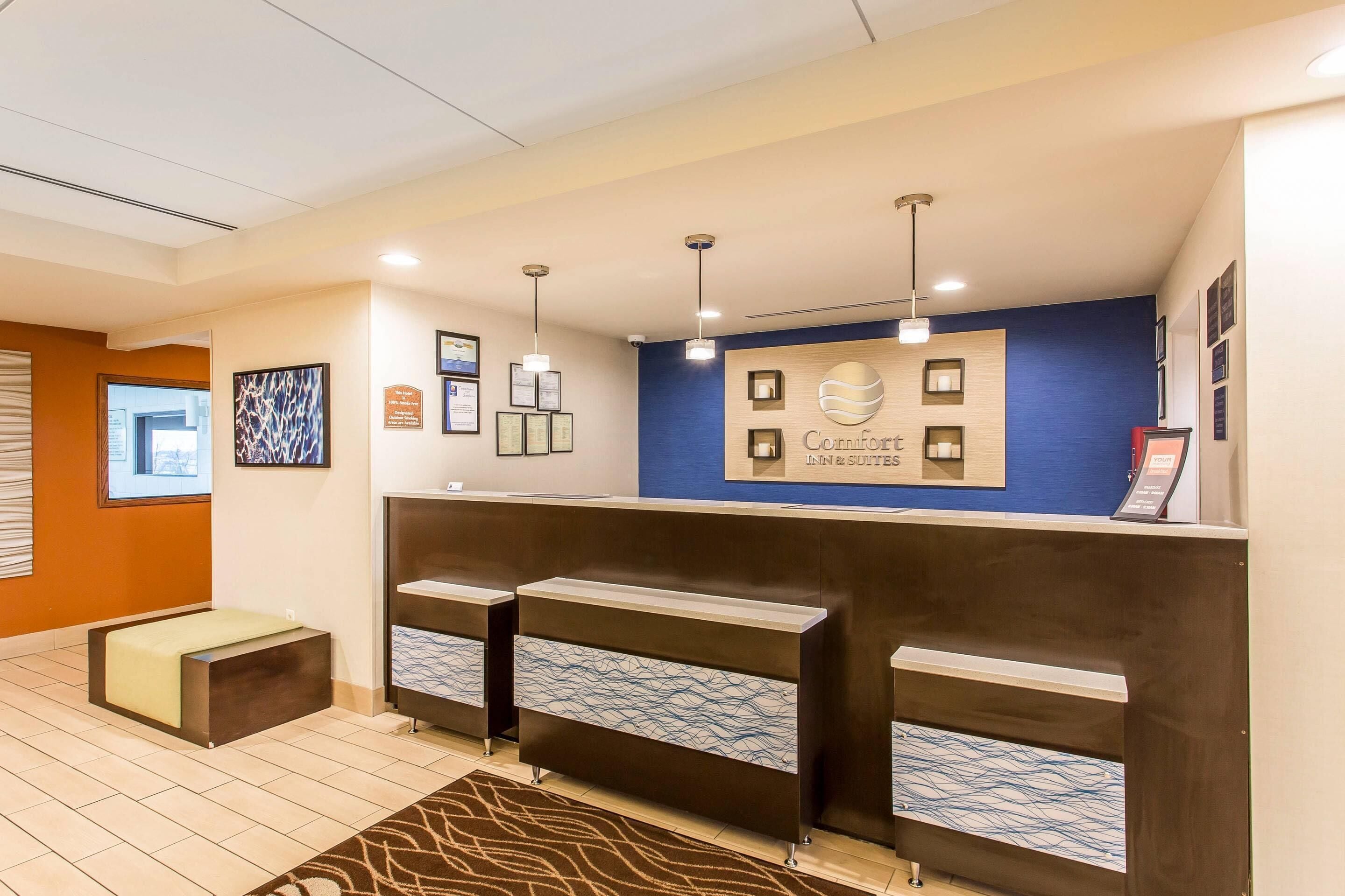 Un área de recepción con una pared azul de acento, cuadros enmarcados y un letrero de 'Comfort Inn & Suites'.