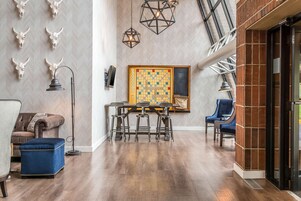 Una habitación amplia con un revestimiento de pared en patrón espiga, suelo de madera, un tablero de ajedrez y una zona de bar con taburetes.