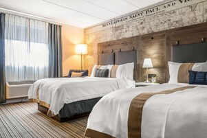Habitación de hotel con dos camas, un mapa grande en la pared y una ventana con cortinas.