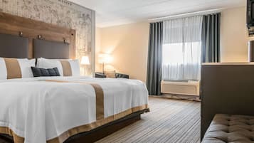 A hotel room with a large bed, a headboard with a map, an air conditioning unit, and a window with curtains.