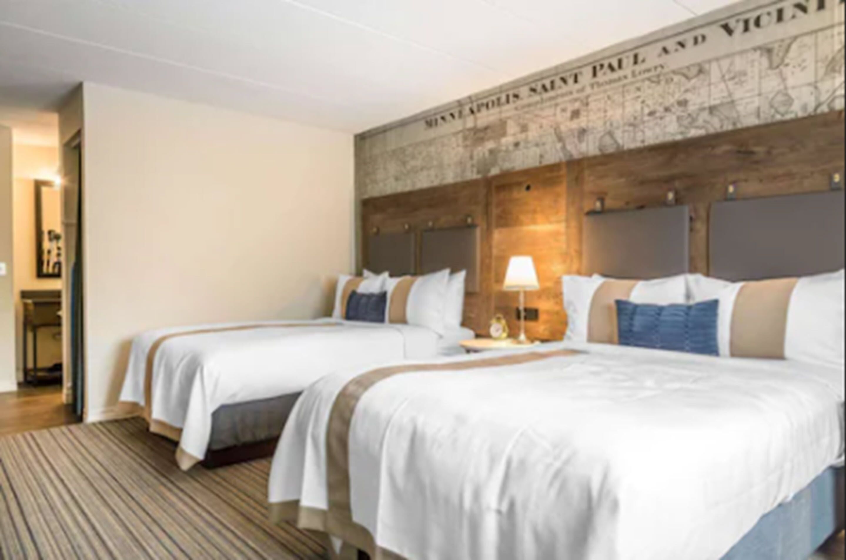 Habitación de hotel con dos camas, un mapa en la pared y suelo de madera.