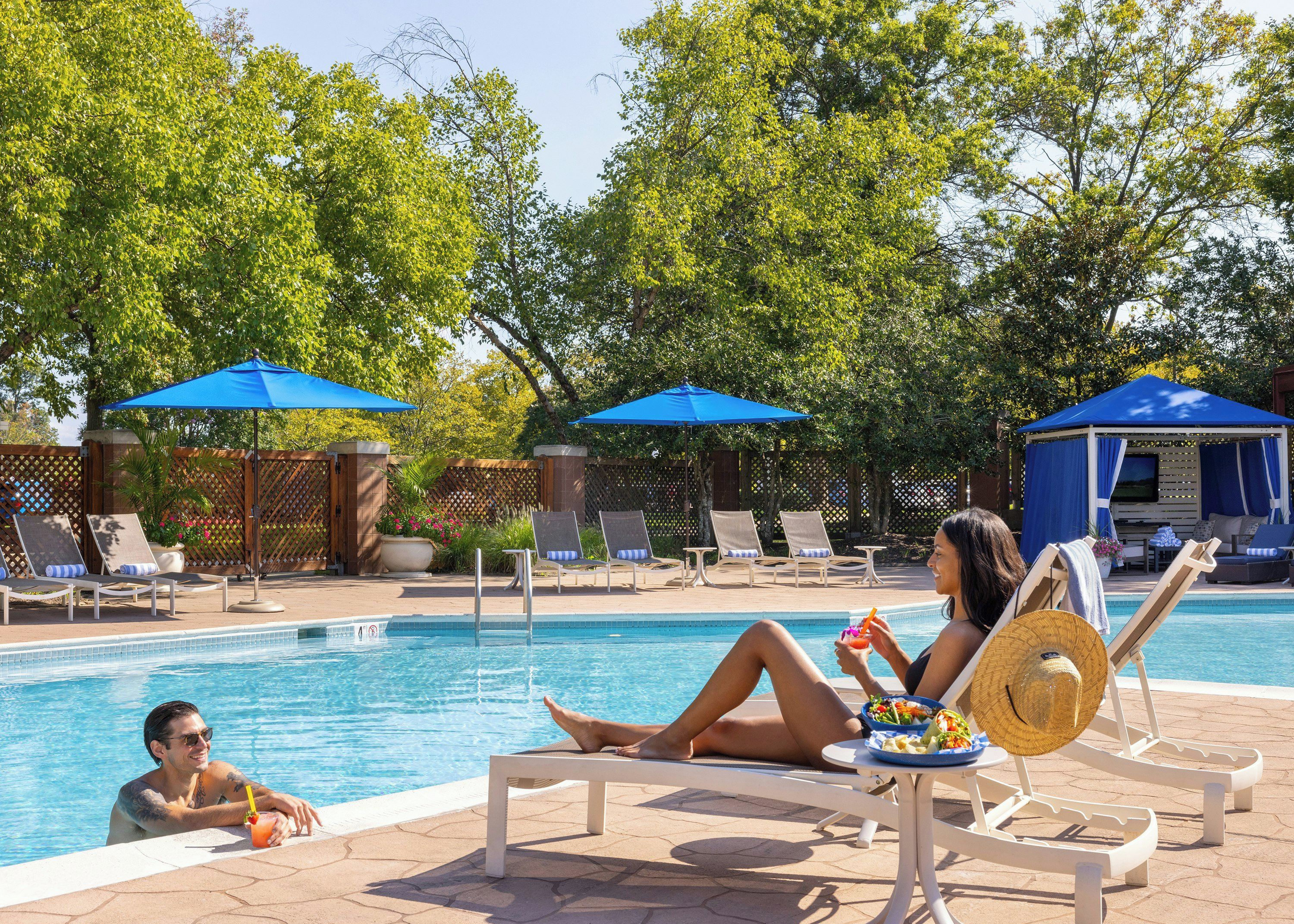 Un espace aménagé au bord de la piscine, avec des chaises longues, des parasols et un cabanon.