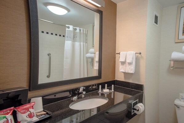 Un baño con un espejo grande, un lavabo, un inodoro y una ducha.