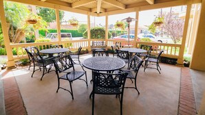A covered patio area with round tables and chairs, a brick floor, and hanging planters. - Fairfield Inn by Marriott Anaheim Hills Orange County (Anaheim)