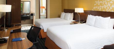 A hotel room with two beds, a desk, a chair, a telephone, and a mirror.