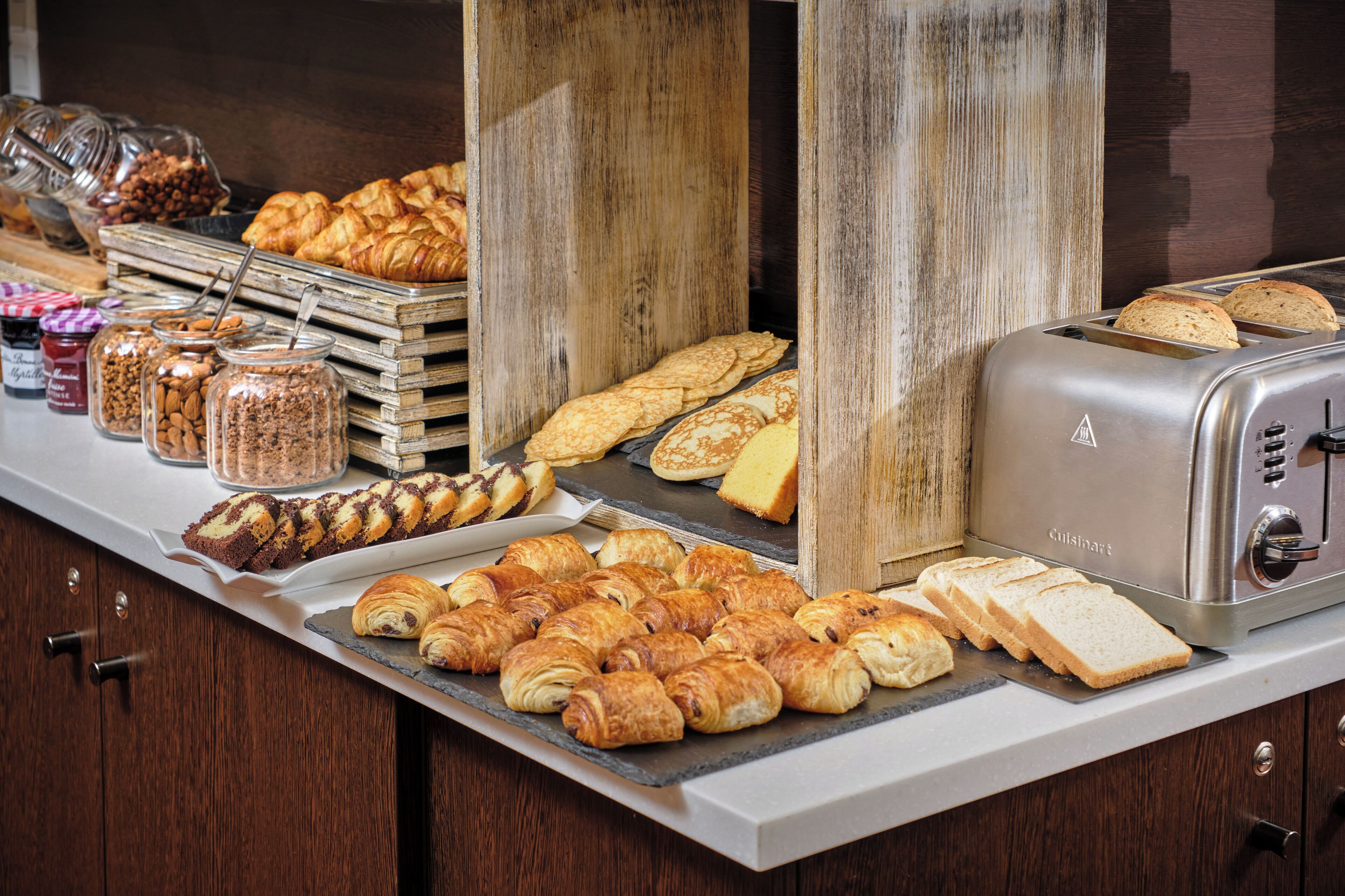 Un buffet proposant une variété de viennoiseries, de sandwichs et de pains.