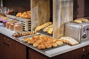 Un bufé con diversos pasteles, sándwiches y pan.