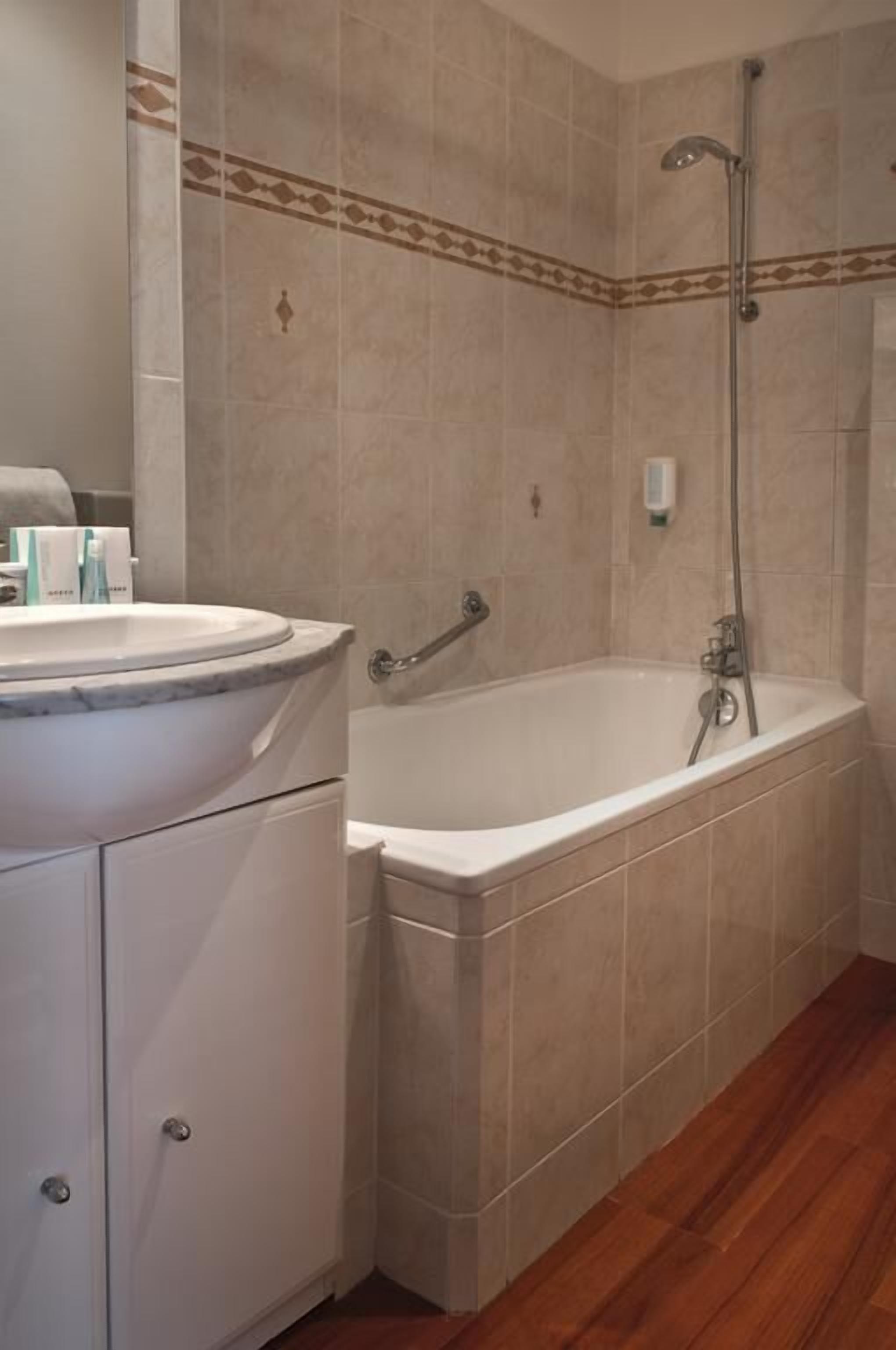 A bathroom with a bathtub, a shower, and a vanity with a sink.