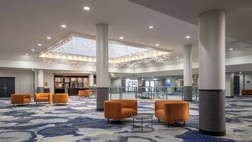 Un hall d’entrée spacieux, doté d’un haut plafond, de grandes colonnes et d’un tapis à motifs.
