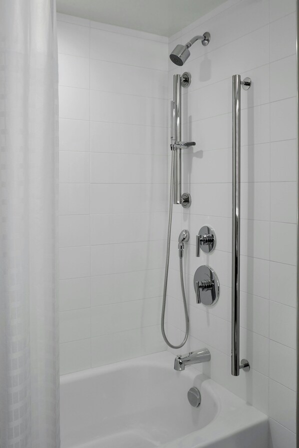 Une salle de bain moderne dotée d’une baignoire, d’une douche avec un pommeau de douche à main et d’un pommeau de douche vertical à effet pluie.
