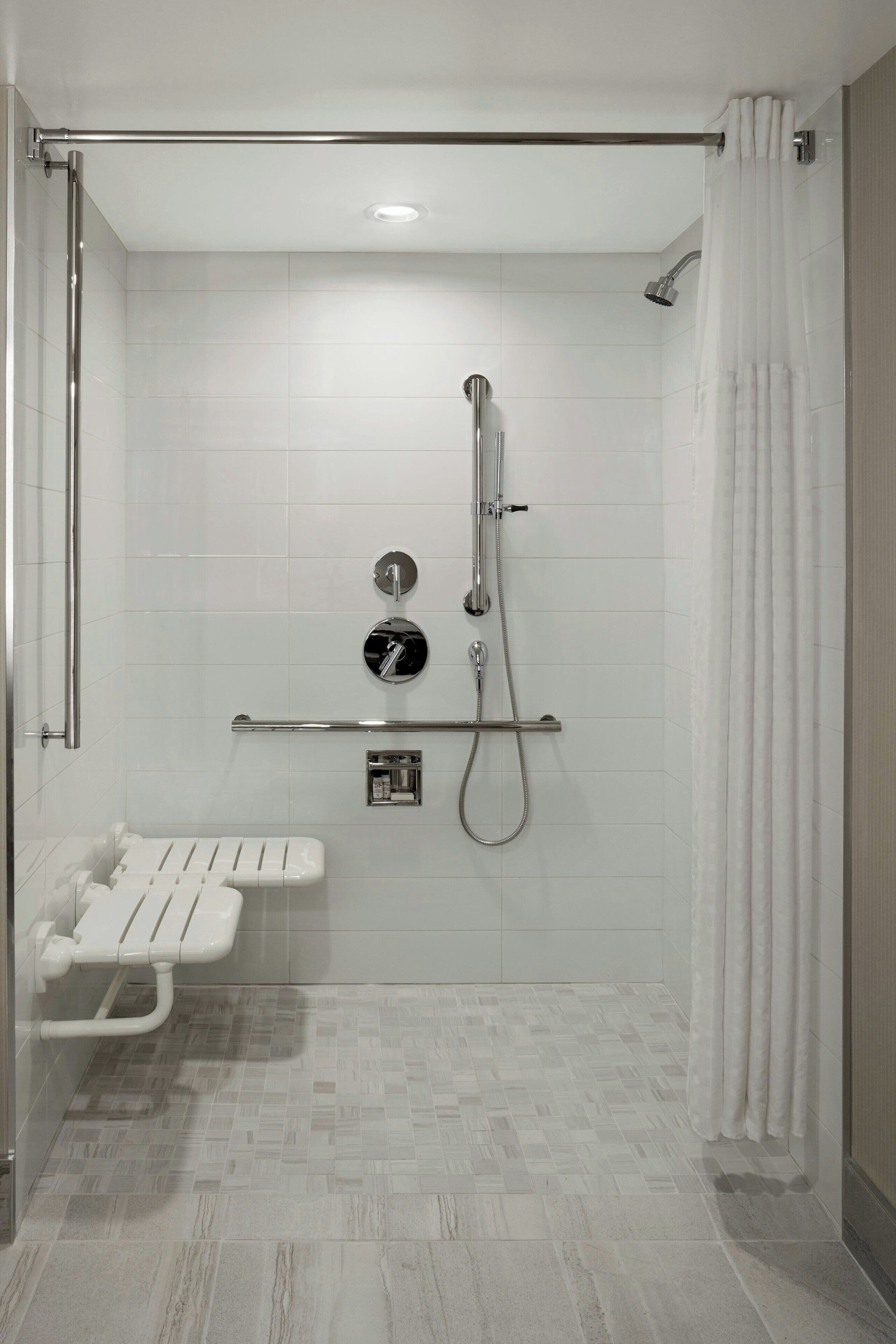 Une salle de bain moderne équipée d’une douche, de toilettes et d’un banc.