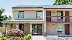 A two-story building with a covered entrance, a parking area, and a small garden with various plants. - Days Inn by Wyndham Winston Salem North (Winston-Salem)
