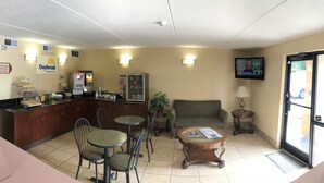 A breakfast area with a counter, chairs, a sofa, a coffee table, and a TV screen. - Days Inn by Wyndham Winston Salem North (Winston-Salem)
