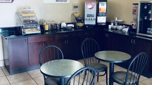 A breakfast area with a counter, coffee machines, and seating. - Days Inn by Wyndham Winston Salem North (Winston-Salem)