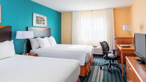 Ett hotellrum med två sängar, ett skrivbord, en stol, en tv och ett fönster med gardiner.