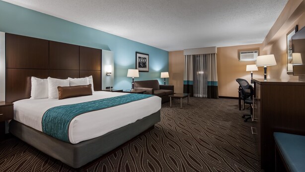 A hotel room with a large bed, a desk, a chair, and a wardrobe. - Best Western Plus Galleria Inn & Suites (Memphis)