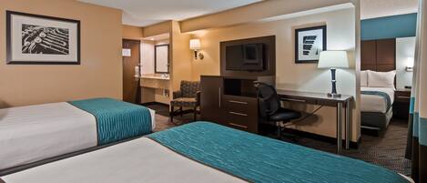A hotel room with two beds, a desk, a chair, a TV, and a bathroom.